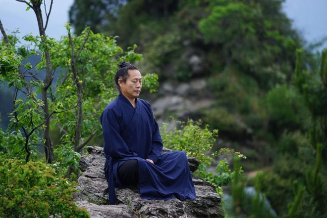 Monian Meditation Incense – a man in traditional robes meditating on a mountain rock, embracing nature and Zen tranquility.