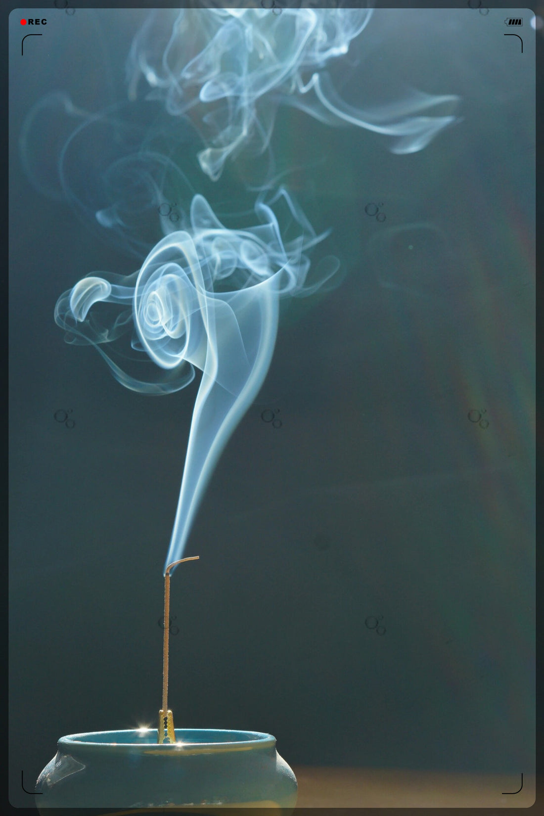 A single incense stick gently burns in a ceramic holder, releasing spirals of fragrant smoke into a tranquil space — evoking stillness, clarity, and the meditative spirit of Monian.