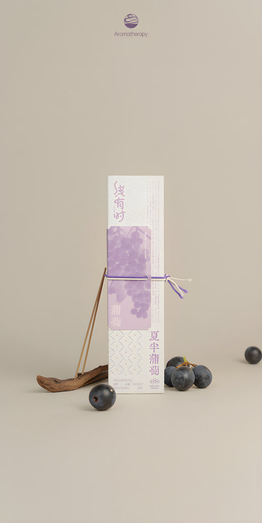 Cream-and-purple grape incense package tied with a purple cord and displayed with dark fruit and a wooden spoon.