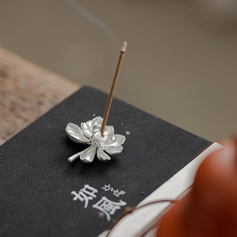 Handcrafted tin lotus incense holder placed on a tea table, radiating calm with its elegant metallic bloom.