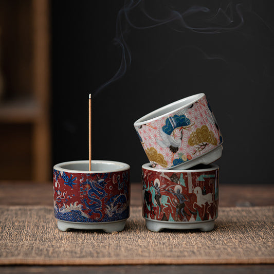 Three patterned incense holders, with a lit stick in one holder.