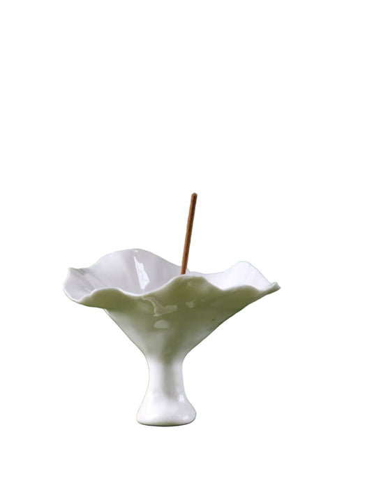A handmade ceramic incense holder shaped like an open flower, holding a lit stick of incense—evoking natural grace, upward energy, and meditative stillness.