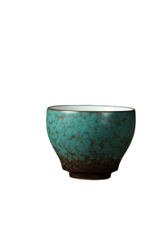 Turquoise ceramic cup on a wooden surface with a gray background