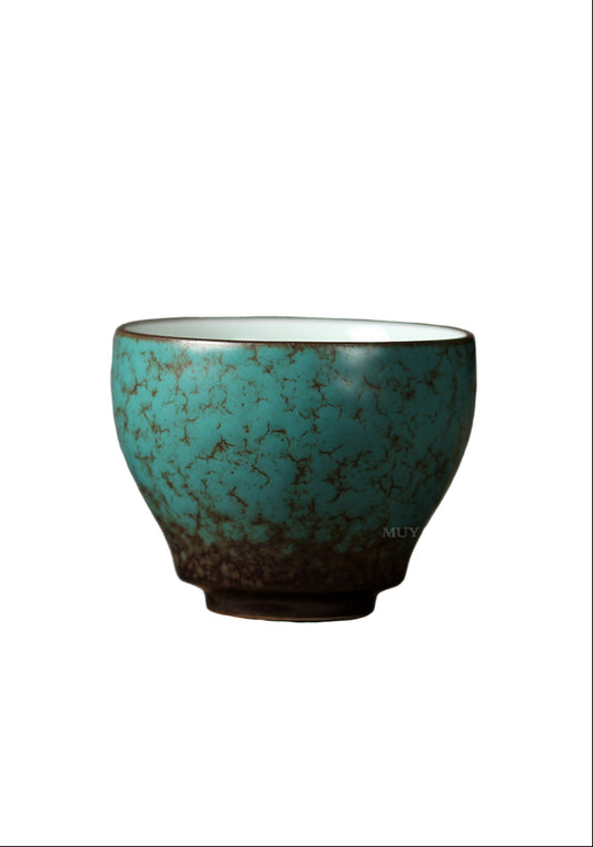 Turquoise ceramic cup on a wooden surface with a gray background