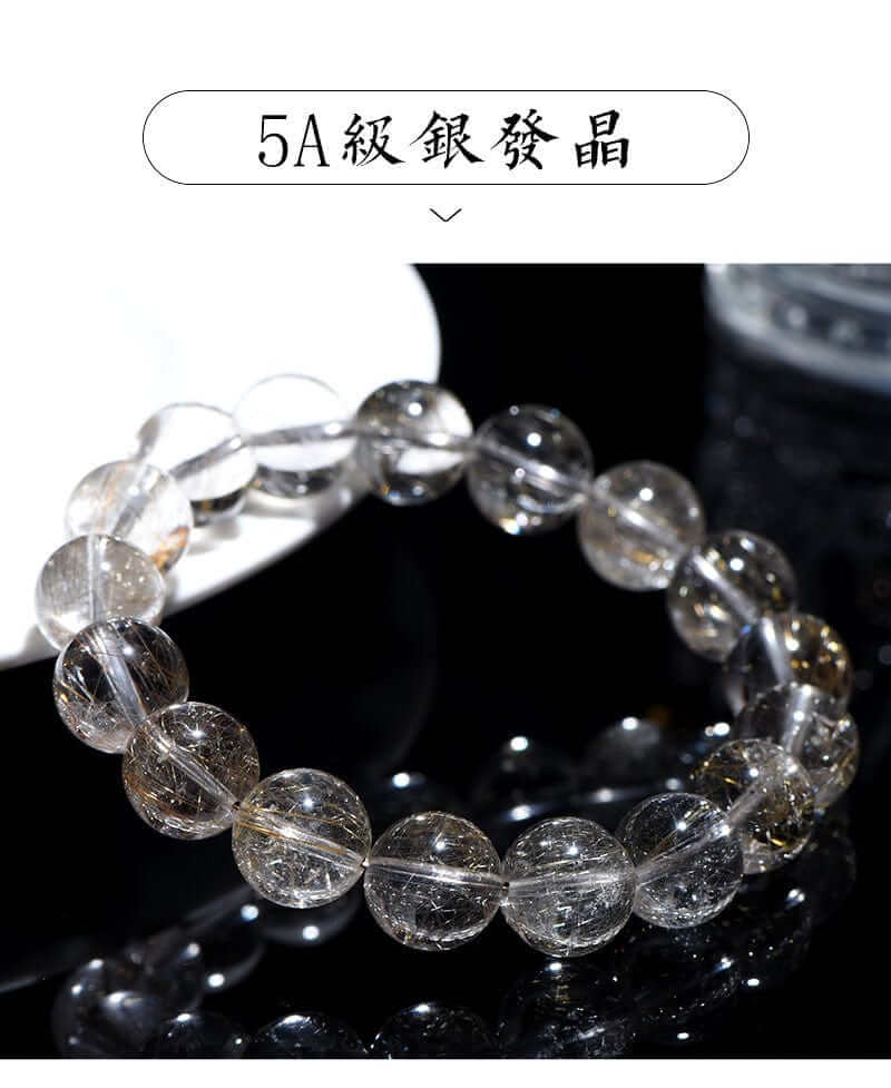 Full bracelet view of natural silver rutilated quartz laid on a white ceramic plate.
