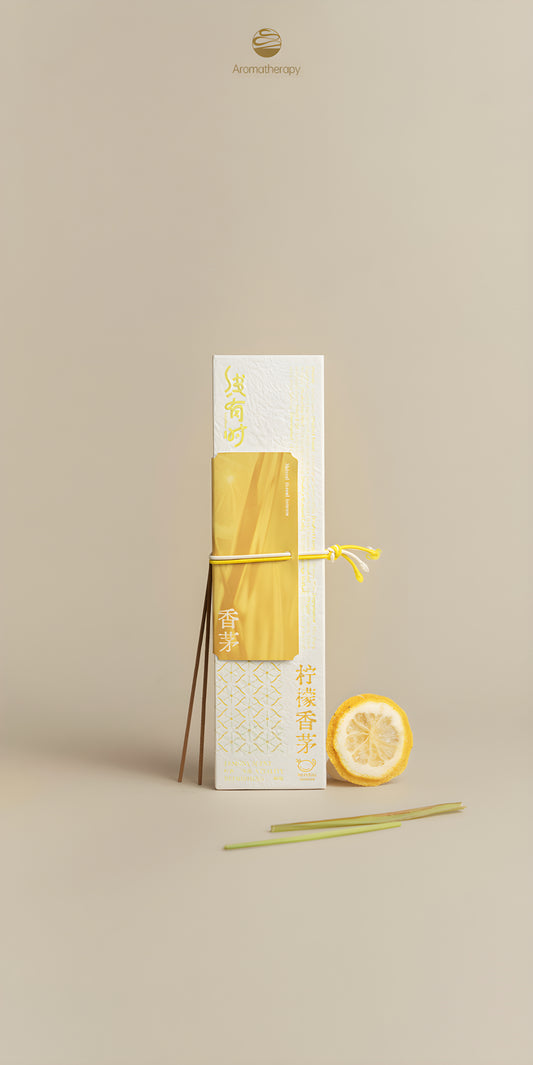 Lemongrass incense box with incense sticks, a lemon half and green stems on a beige background.