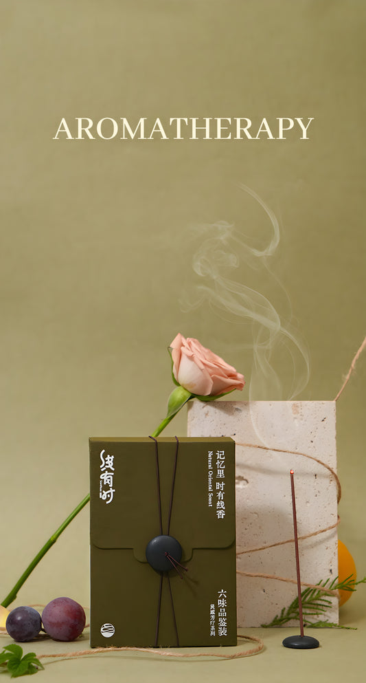 Olive-green incense discovery box displayed with a rose, grapes and a burning incense stick.