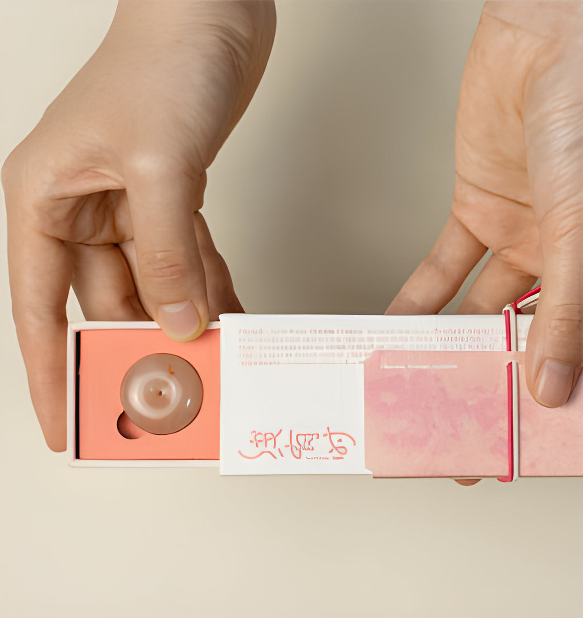 Hands sliding open the pink rose incense box to reveal the round holder in its fitted tray.