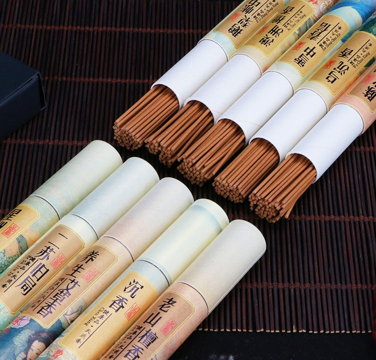 Incense sticks in white cylindrical packaging on a dark textured surface