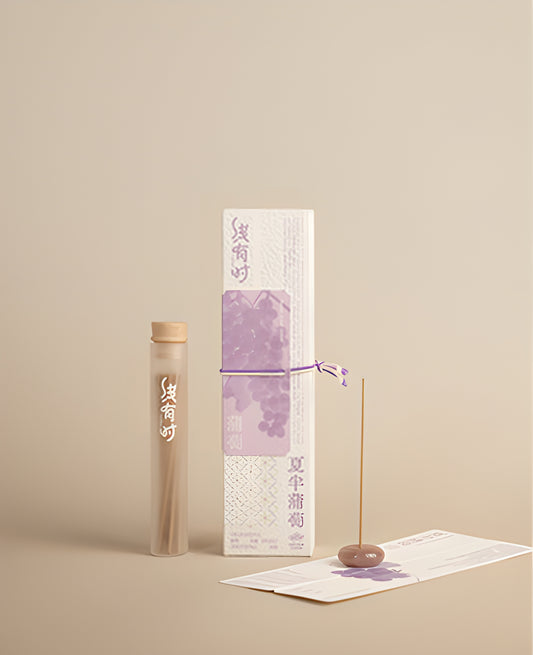 Grape incense packaging and a slim storage tube beside an upright incense stick in a round holder.