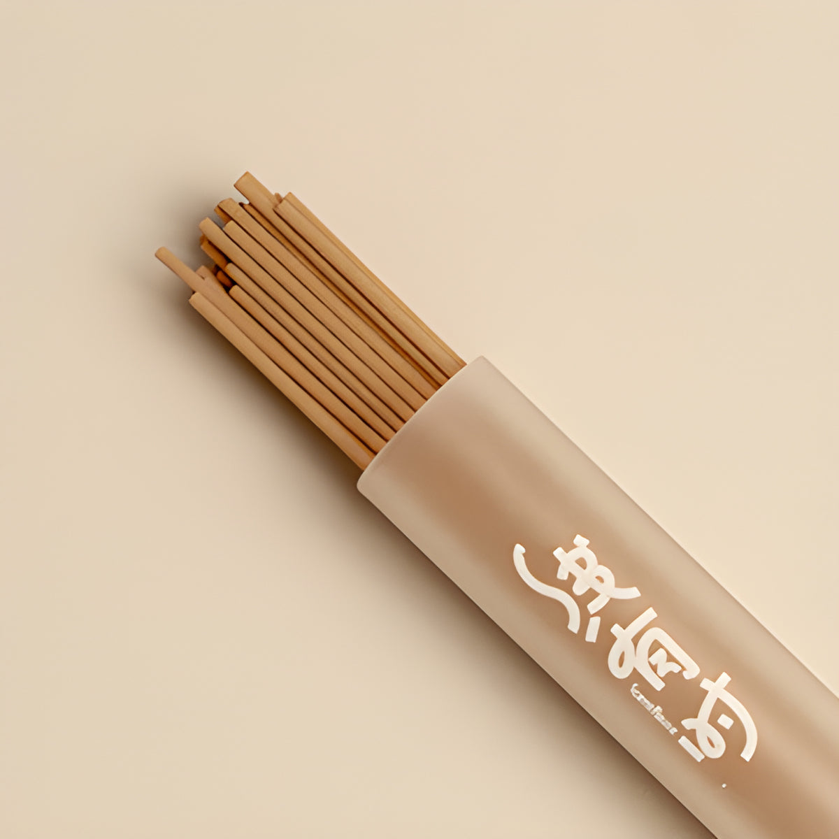 Close-up of slender brown grape incense sticks extending from a frosted storage tube.
