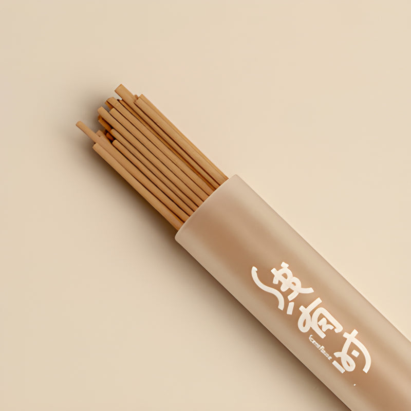 Close-up of slender brown grape incense sticks extending from a frosted storage tube.