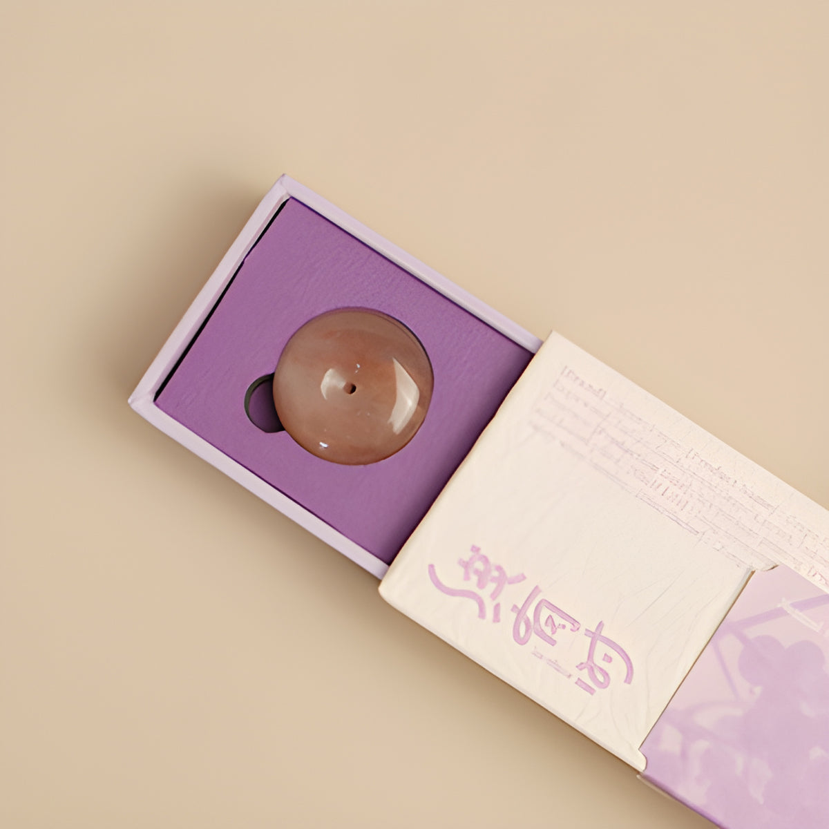 Round incense holder nestled in the purple tray of the grape incense box.