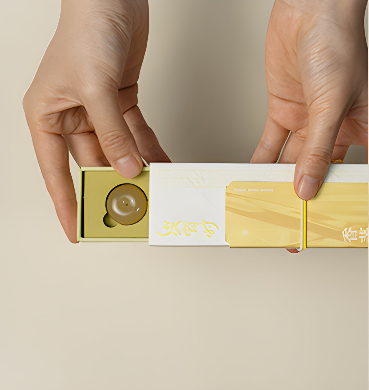 Hands sliding open the lemongrass incense box to reveal the yellow incense holder.