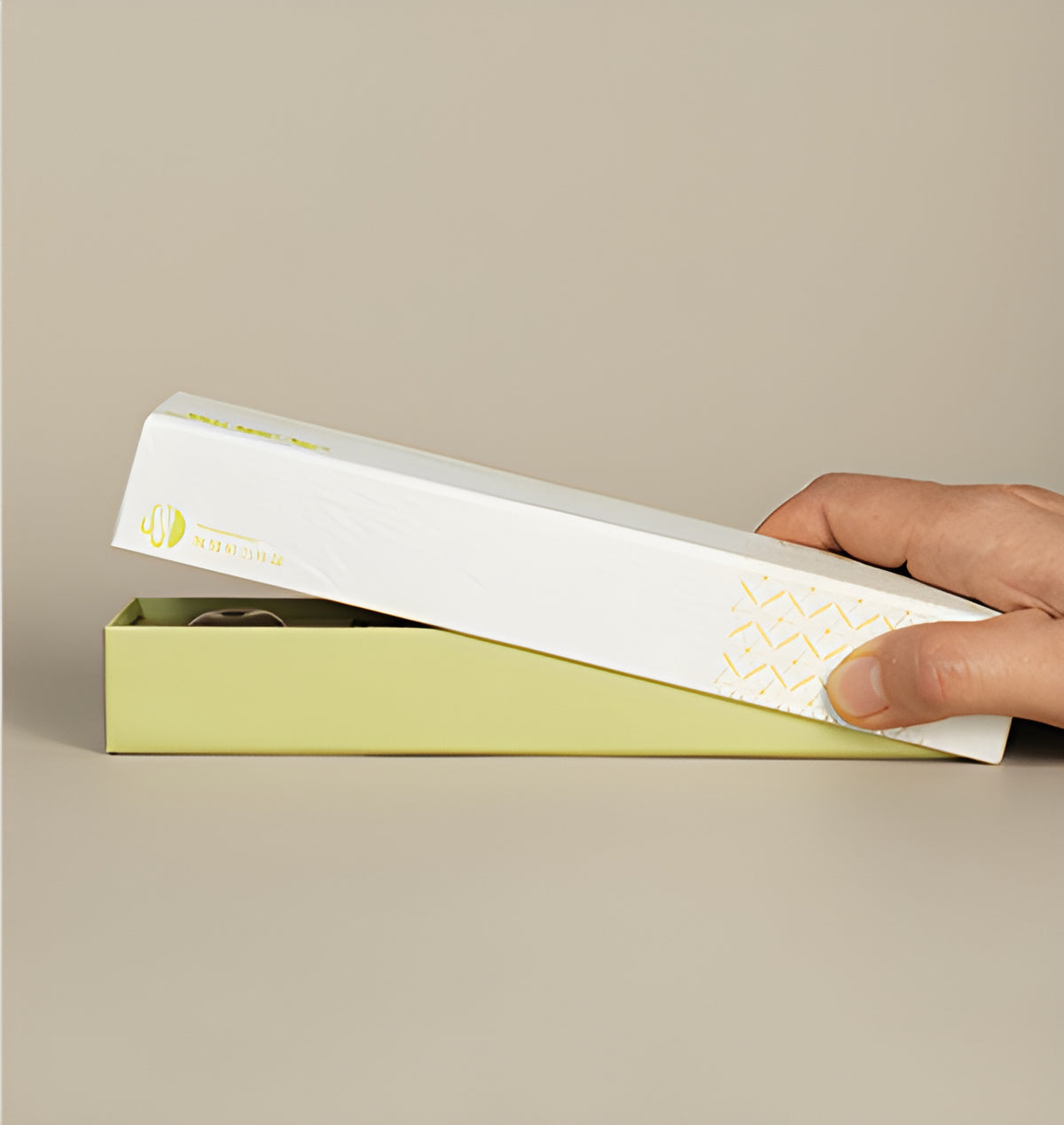 Hands opening the white-and-yellow lemongrass incense presentation box.