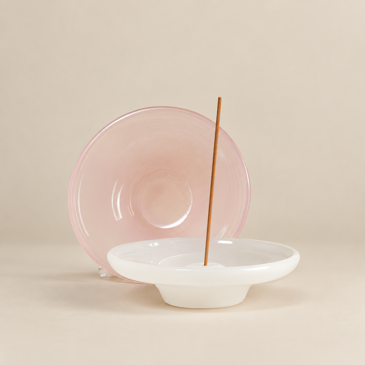 Incense burner with a translucent pink circular back and white ash-catching bowl holding an incense stick.