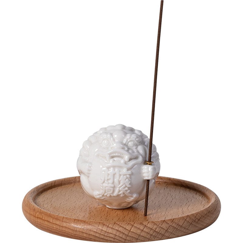 A handcrafted ceramic incense holder shaped like a seated guardian lion, holding a stick of incense upright—projecting protective stillness and ceremonial presence.