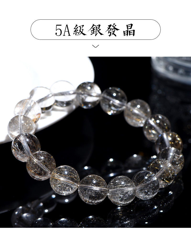 Full bracelet view of natural silver rutilated quartz laid on a white ceramic plate.