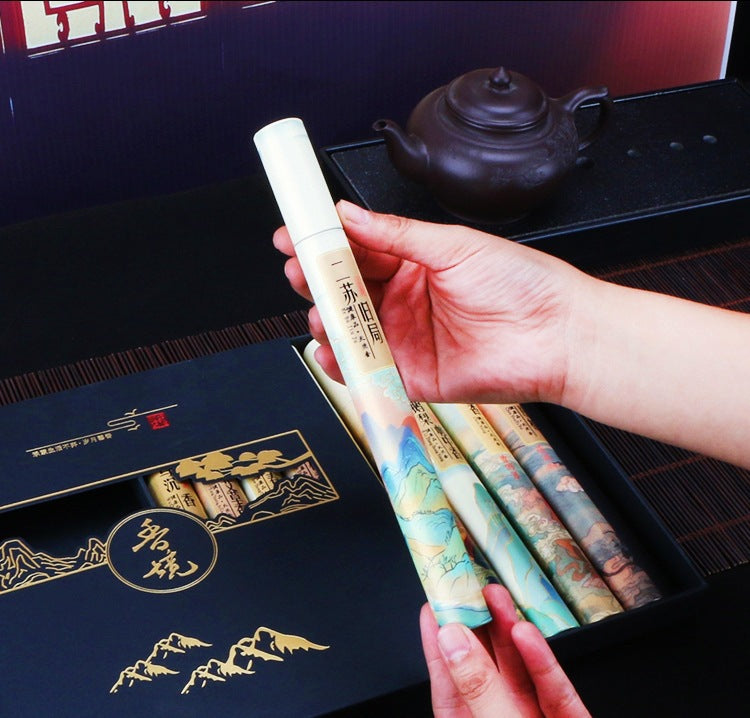 Hand holding three cylindrical products with a decorative cover, set against a tea-themed background.