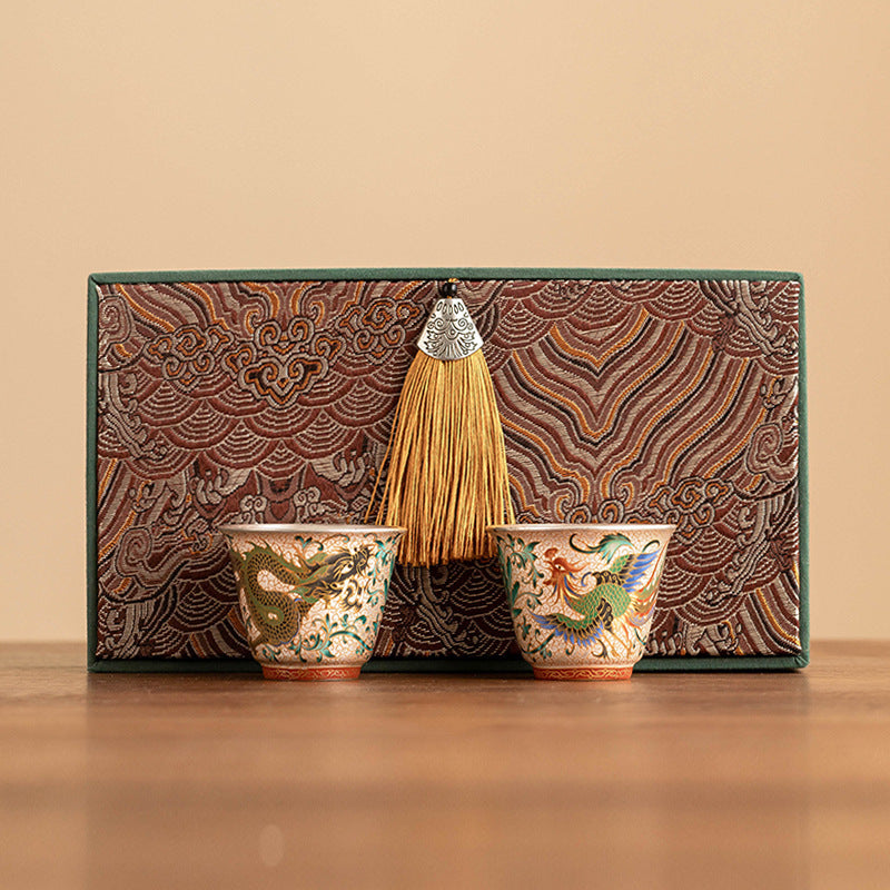 Decorative set with two ornate cups and a broom against a patterned background