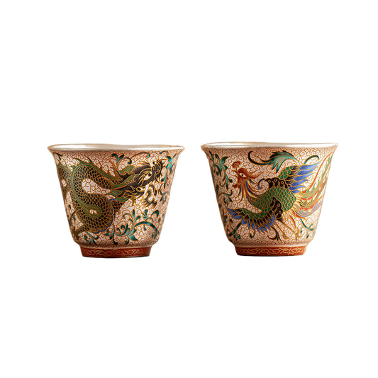 Two ceramic cups with intricate dragon designs on a wooden surface.