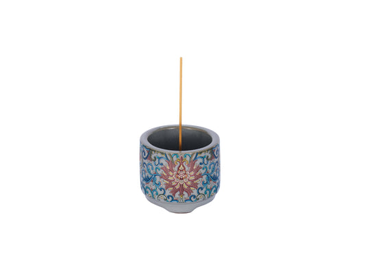 Decorative incense holder with a single incense stick on a white background